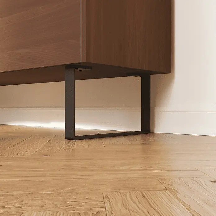 HEVVA Möbelfuß-Set LUXEMBURG - L x B x H: 35 x 4 x 15 cm, Metall, 2 Stk. - Brauner Holzschrank mit dunklem Metallfuß, über einem Holzfußboden mit Lichtleiste darunter.