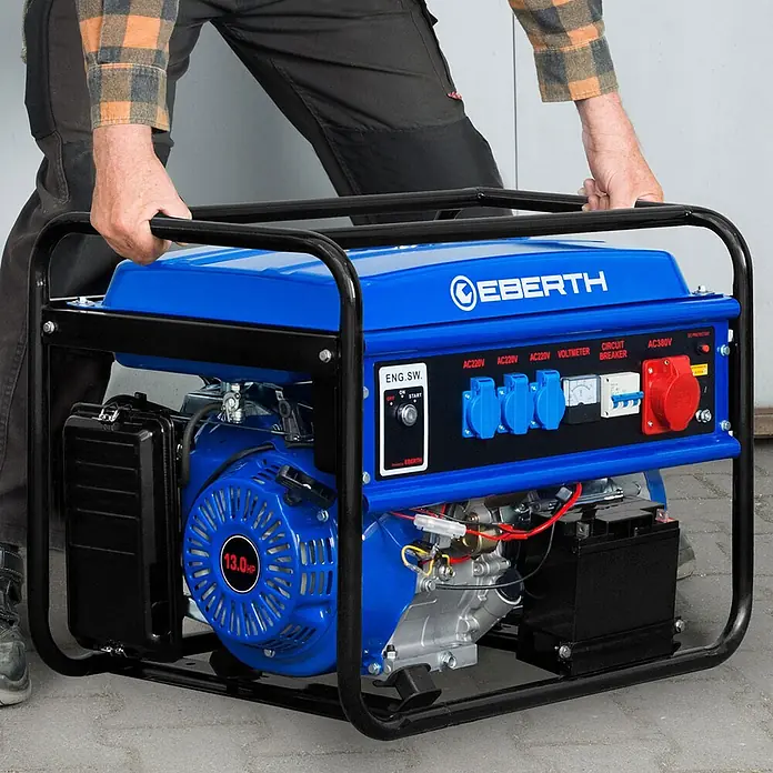 EBERTH Stromerzeuger 5500 Watt 13PS Leistung E-Start 3-Phasen - Nennleistung: 5 kW, Tankvolumen: 25 l - Eine Person hebt einen blauen und schwarzen tragbaren Stromerzeuger an seinem schwarzen Metallrahmen, sichtbar ist das Bedienfeld und der Motor.