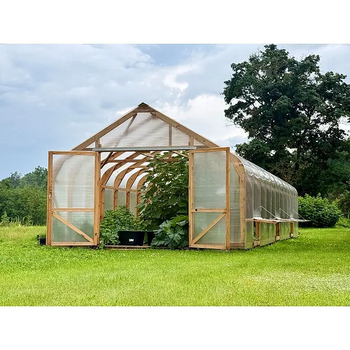 Garten Dream Gewächshaus Classic Wood - 450 x 800 cm, Material Seitenwand: Kunststoff, 10 mm, Braun - Holzgewächshaus mit durchscheinenden Paneelen und geöffneten Türen, voller Pflanzen.