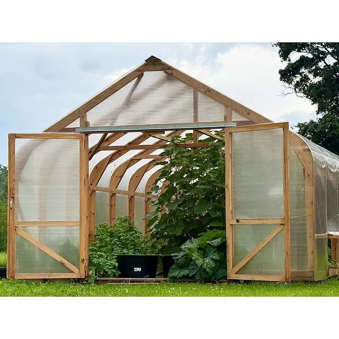 Garten Dream Gewächshaus Classic Wood - 450 x 800 cm, Material Seitenwand: Kunststoff, 10 mm, Braun - Gewächshaus mit Holzrahmen und transparenten Paneelen, offene Türen zeigen grüne Pflanzen darin.