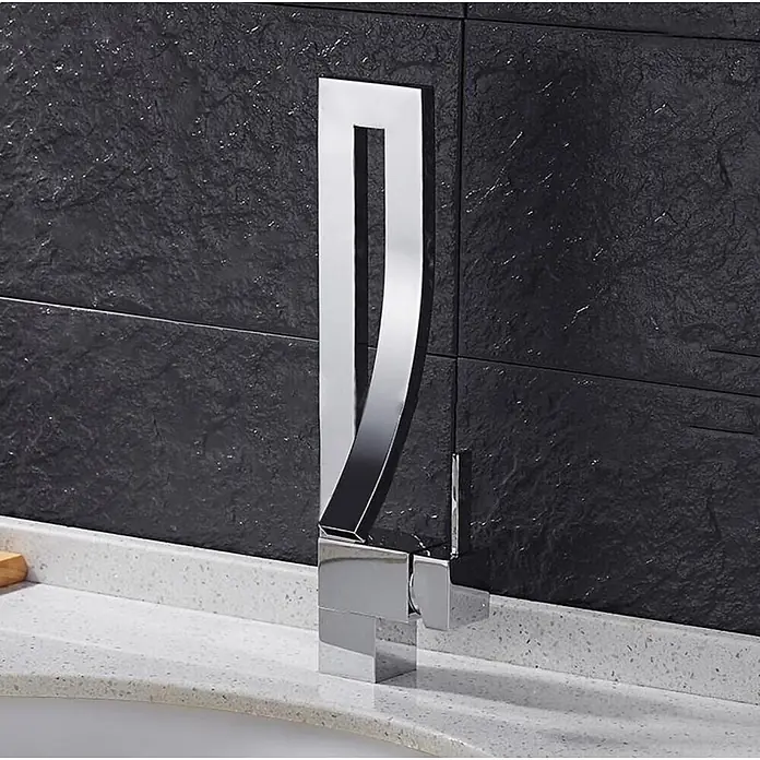 Hudor Waschtischarmatur Enipée 005 - Hochglänzend - Glänzender Chrom-Wasserhahn mit geschwungenem Design, auf einer weißen Arbeitsplatte vor einer dunklen Fliesenwand.