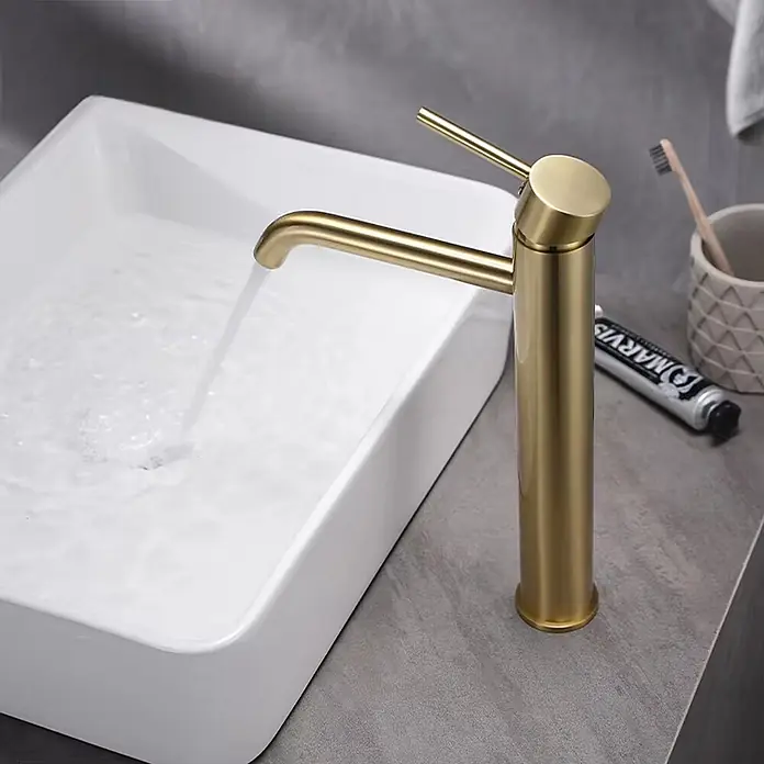 Hudor Waschtischarmatur Scamandre 7635 - Seidenmatt - Hoher mattgoldener Badarmatur mit Wasserlauf in ein rechteckiges weißes Waschbecken.