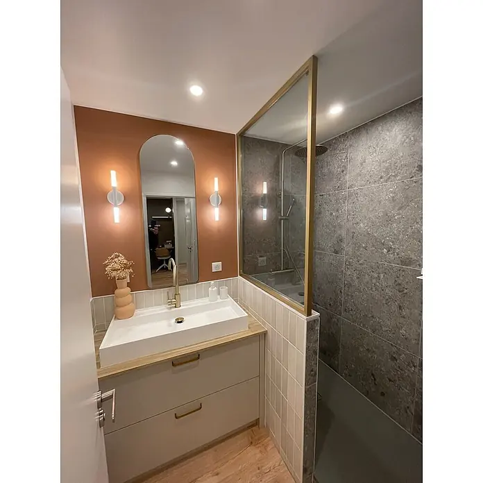 Hudor Waschtischarmatur Scamandre 6565 - Seidenmatt - Moderner Badezimmerwaschtisch mit weißem Waschbecken, heller Holzplatte, hellgrauen Schubladen und Messingakzenten in einem modernen Badezimmer.