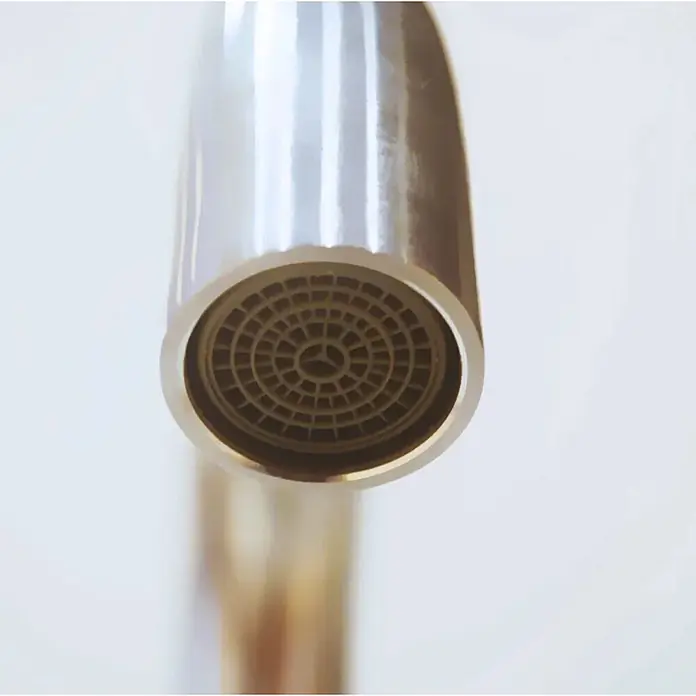 Hudor Spültischarmatur - Seidenmatt - Nahaufnahme eines glänzenden Metall-Wasserhahnauslaufs mit kreisförmigem, dunkel vergittertem Perlator.