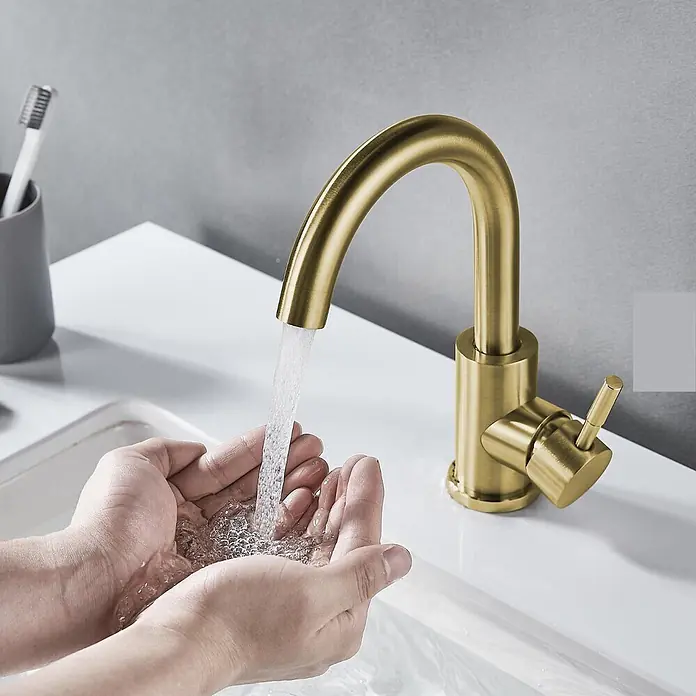 Hudor Waschtischarmatur Scamandre 0581 - Seidenmatt - Mattgoldener Badarmatur spendet Wasser in gefaltete Hände im Waschbecken.
