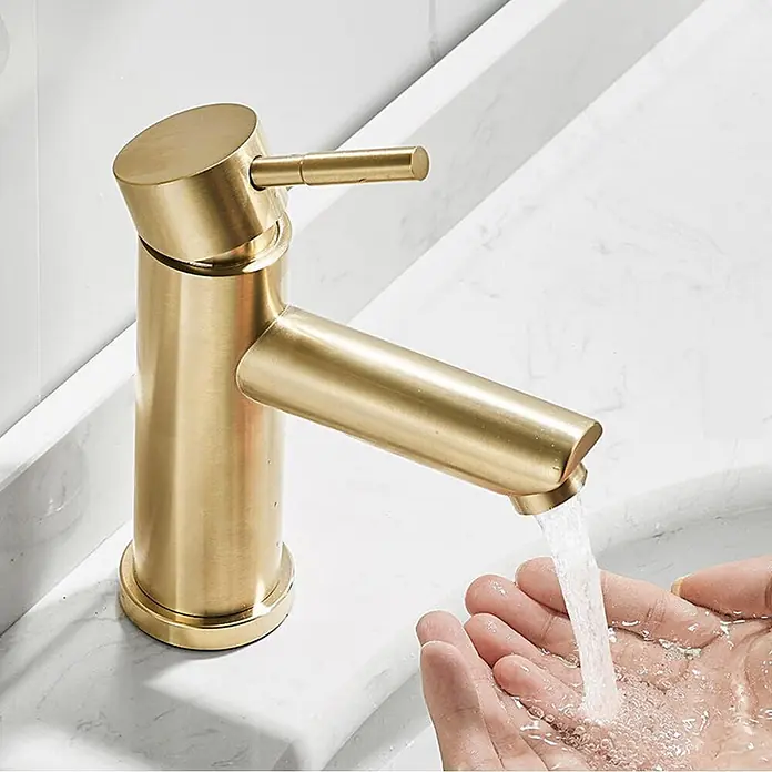 Hudor Waschtischarmatur Scamandre 6478 - Seidenmatt - Moderner, matter goldfarbener Einhebelmischer gießt Wasser in Hände in einem weißen Waschbecken, zeigt elegantes Design und Funktion.