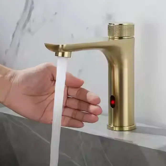 Hudor Waschtischarmatur Scamandre 1427 - Seidenmatt - Goldener Sensor-Wasserhahn mit fließendem Wasser über einer Hand.