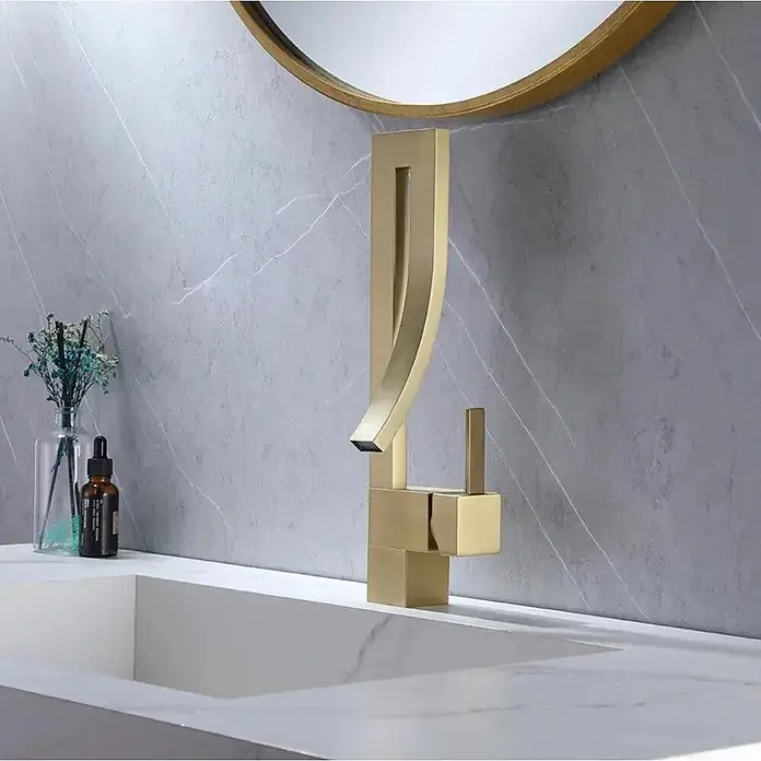 Hudor Waschtischarmatur 6836 - Hochglänzend - Moderner goldfarbener skulpturaler Wasserhahn auf einer weißen Waschtischplatte installiert.