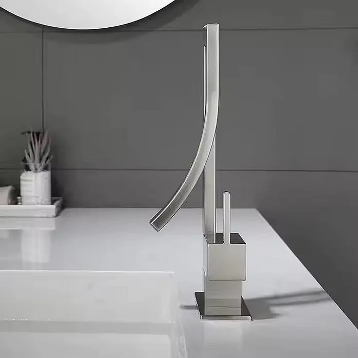 Hudor Waschtischarmatur - Seidenmatt - Moderner Wasserhahn aus gebürstetem Nickel mit gebogenem Auslauf und quadratischem Sockel, an einem weißen Waschbecken installiert.