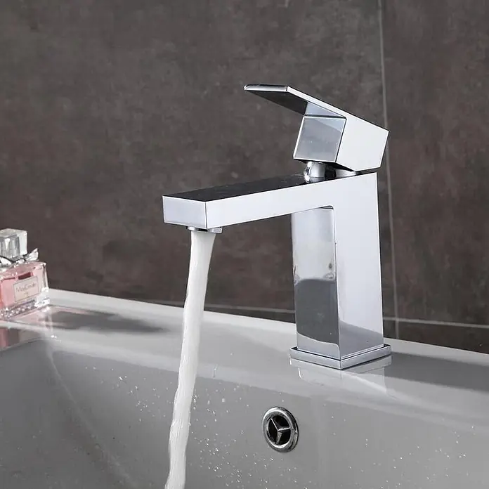 Hudor Waschtischarmatur Enipée 013 - Hochglänzend - Glänzender Chrom-Wasserhahn mit quadratischem Design, Wasser läuft in ein weißes Waschbecken.
