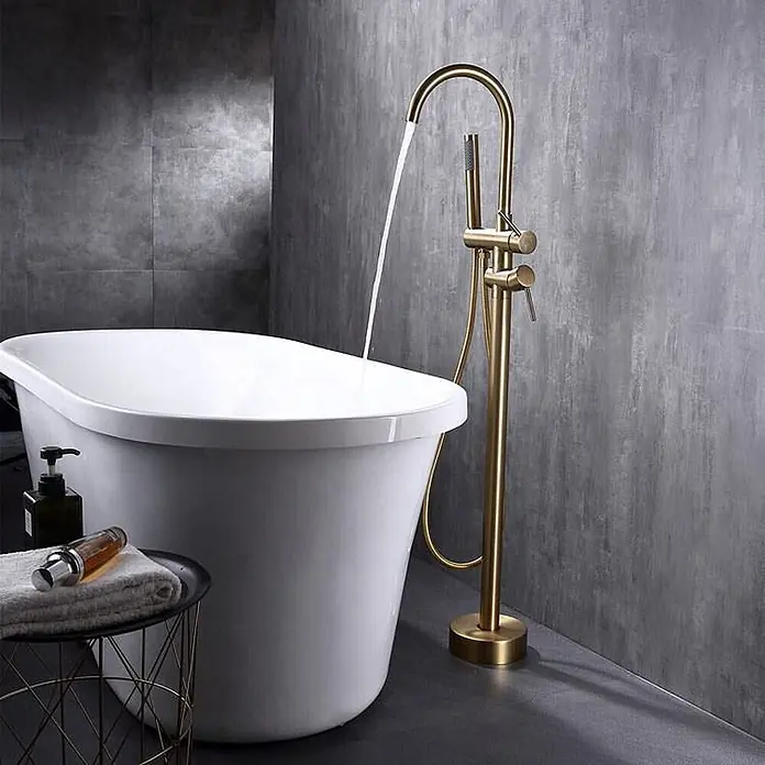 Hudor Badewannenarmatur Scamandre 007 - Seidenmatt - Messingfarbene bodenstehende Armatur füllt eine moderne weiße freistehende Badewanne.