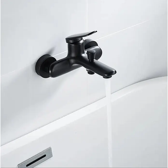 Hudor Badewannenarmatur Céphise 039 - Matt - Mattschwarze wandmontierte Badewannenarmatur mit Einhebelmischer, die Wasser in eine weiße Wanne gießt.