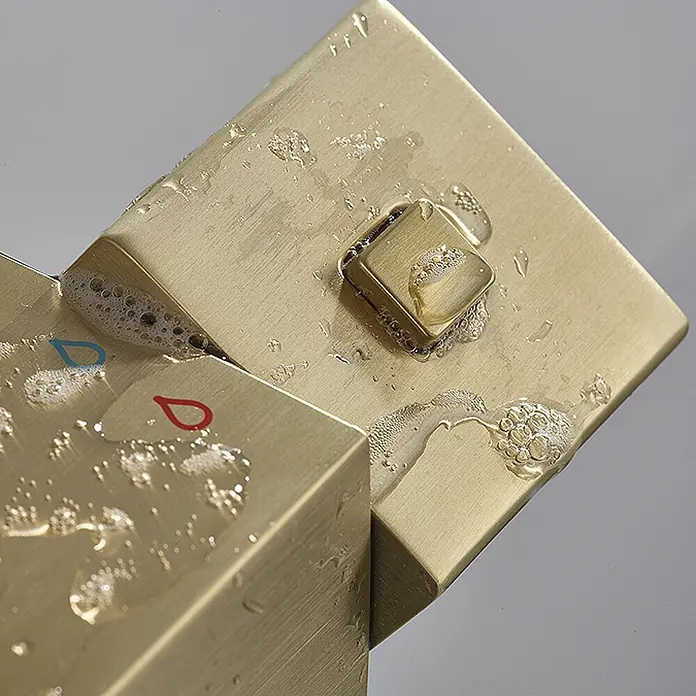 Hudor Duschsystem Scamandre SC428 Thermostat -  - Gebürstete gold/messing Duscharmatur mit quadratischem Drehknopf, bedeckt mit Wassertropfen und roten/blauen Heiß-/Kalt-Symbolen.