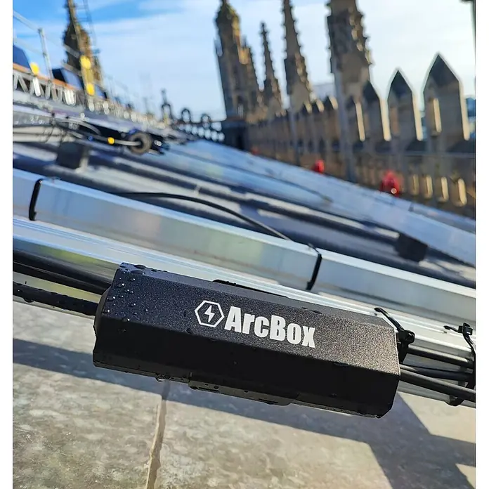 Kabelbox ArcBox Solar-Brandschutz-Anschlussgehäuse - Schwarz, L x B x H: 48 x 150 x 50 mm - Schwarzes ArcBox Gerät, nass mit Wassertropfen, an einer Solarmodulschiene montiert, zur Kabelverwaltung.