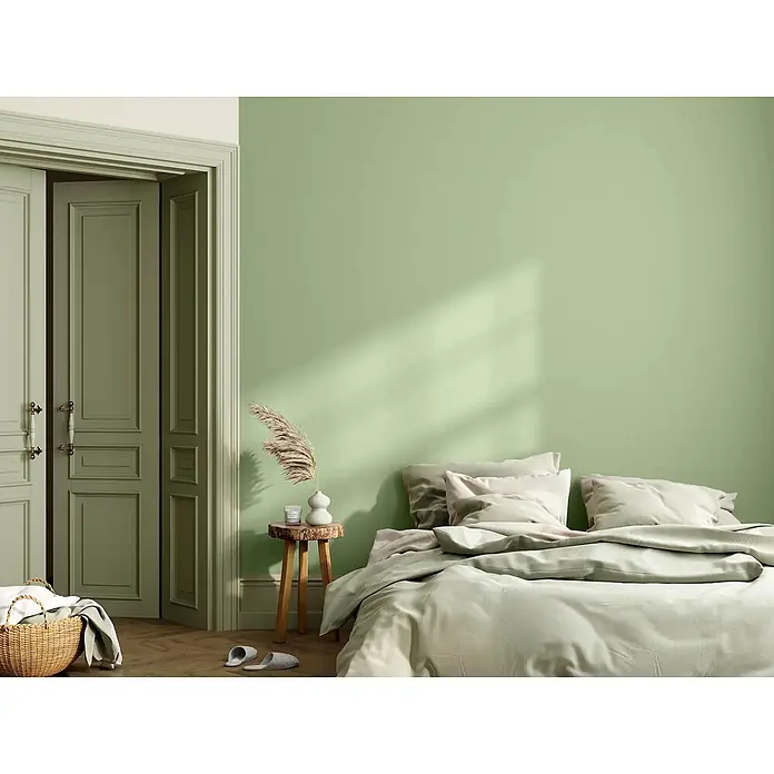 Caleo Color Wandfarbe Lehmfarbe Salbeiduft - Salbeiduft, Matt, 5 l - Ein ruhiges Schlafzimmer mit hellgrünen Wänden und passenden Türen, ausgestattet mit einem Bett mit weicher, neutraler Bettwäsche.