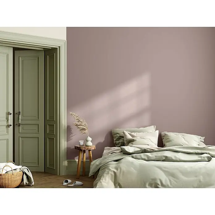 Caleo Color Wandfarbe Lehmfarbe Abenddämmerung - Abenddämmerung, Matt, 0,15 l - Weiche, hellgrüne Bettwäsche mit einer Bettdecke und Kissen auf einem Bett in einem minimalistischen Schlafzimmer.