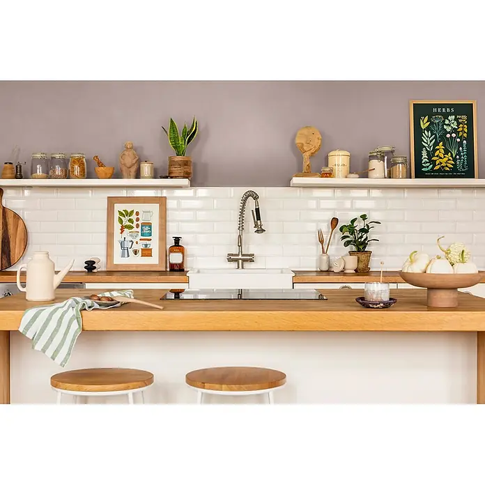 Caleo Color Wandfarbe Lehmfarbe Abenddämmerung - Abenddämmerung, Matt, 0,15 l - Moderne Küche mit Holz-Arbeitsplatte, weißen Metrofliesen, offenen Regalen, Spüle, Armatur und diversen Deko- und Küchenutensilien.