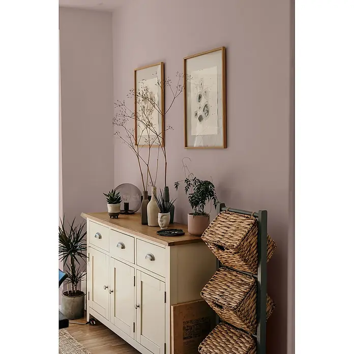 Caleo Color Wandfarbe Lehmfarbe Abenddämmerung - Abenddämmerung, Matt, 0,15 l - Cremefarbenes Sideboard mit Holzplatte, dekoriert mit Pflanzen. Dunkles Regal mit drei geflochtenen Körben.
