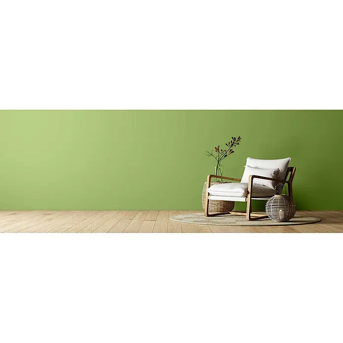 Caleo Color Wandfarbe Lehmfarbe Gingko - Gingko, Matt, 10 l - Moderner Sessel mit weißen Polstern und hellem Holzrahmen auf einem Teppich, umgeben von Korbflechte-Deko auf Holzboden.