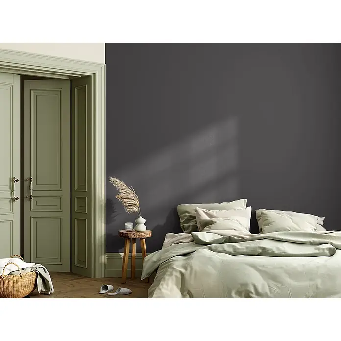 Caleo Color Wandfarbe Lehmfarbe Ebenholz - Ebenholz, Matt, 0,15 l - Hellgrüne Bettwäsche auf einem Bett in einem stilvollen Schlafzimmer.