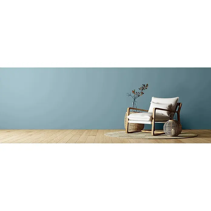Caleo Color Wandfarbe Lehmfarbe Lagune - Lagune, Matt, 10 l - Moderner Sessel mit weißen Kissen und Holzrahmen in einem minimalistischen Raum. Mit hellblauer Wand, Holzboden und Flechtdekor.