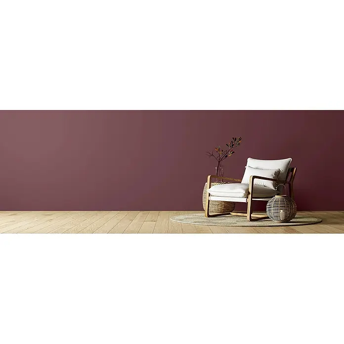 Caleo Color Wandfarbe Lehmfarbe Kaminabend - Kaminabend, Matt, 2,25 l - Ein moderner Sessel mit hellen Polstern und Holzrahmen in einem gemütlichen Raum mit dunkler Akzentwand und hellem Holzboden.