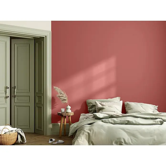 Caleo Color Wandfarbe Lehmfarbe Rosenknospe - Rosenknospe, Matt, 5 l - Schlafzimmer mit korallroter Wand, hellgrünen Türen und weicher grüner Bettwäsche, die einen beruhigenden, stilvollen Kontrast bietet.