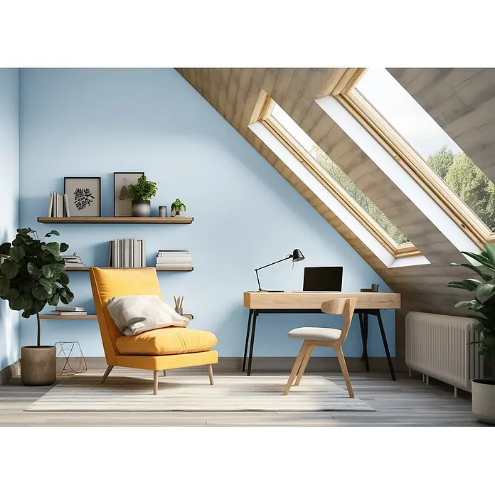 Caleo Color Wandfarbe Lehmfarbe Morgentau - Morgentau, Matt, 2,25 l - Ein helles Dachzimmer-Büro mit hellblauen Wänden, Holztisch, Stuhl, gelbem Sessel und Regalen mit Büchern und Pflanzen unter Dachfenstern.