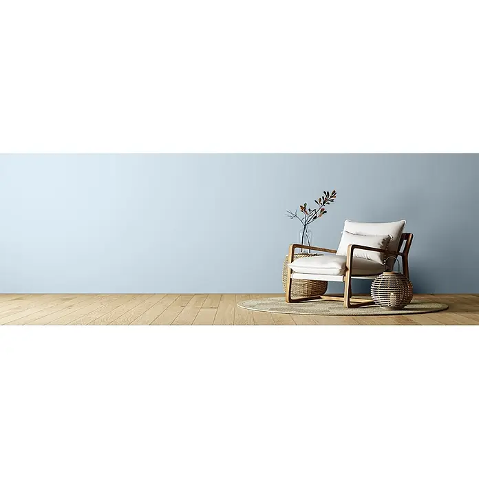 Caleo Color Wandfarbe Lehmfarbe Morgentau - Morgentau, Matt, 2,25 l - Weißer Sessel mit Holzrahmen und Kissen, auf einem runden Teppich in einem Raum mit hellblauer Wand und Holzboden.