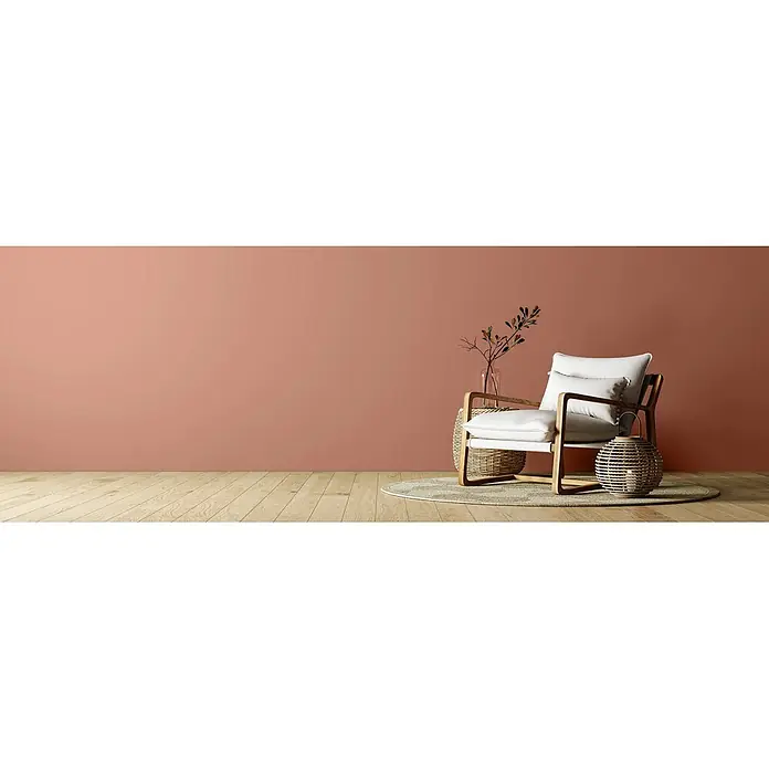 Caleo Color Wandfarbe Lehmfarbe Herbstlaub - Herbstlaub, Matt, 2,25 l - Ein heller Holzstuhl mit weißen Kissen, ein Korbtisch und eine passende Laterne auf einem Teppich.