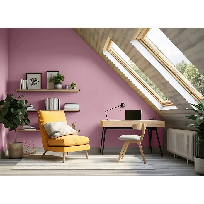 Caleo Color Wandfarbe Lehmfarbe Königsflieder - Königsflieder, Matt, 5 l - Gemütliches Dachzimmer mit rosafarbenen Wänden, gelbem Sessel und Holzschreibtisch unter einem Dachfenster, ideal für Home-Office oder Leseecke.