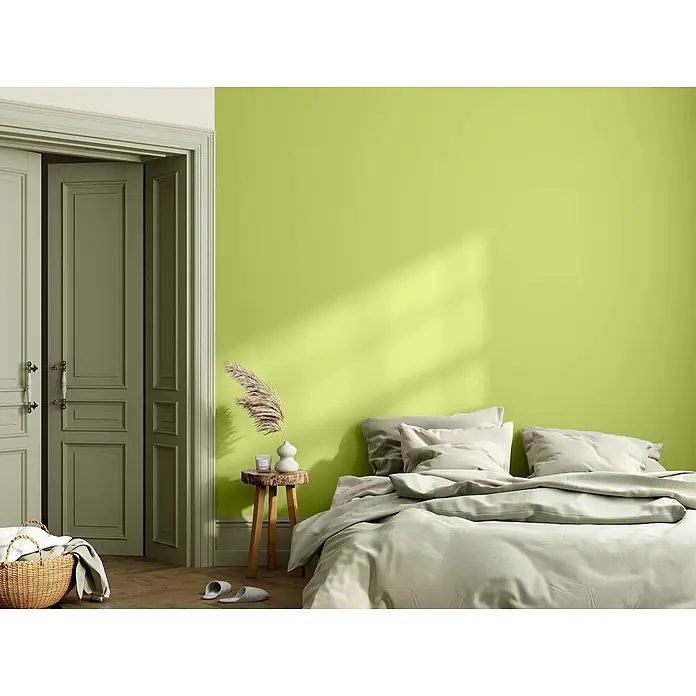 Caleo Color Wandfarbe Lehmfarbe Urzeitfarn - Urzeitfarn, Matt, 5 l - Eine ruhige Schlafzimmerszene mit einem Bett mit weicher salbeigrüner Bettwäsche, einem klassischen salbeigrünen Türrahmen und einem kleinen Holzbeistelltisch mit Deko.