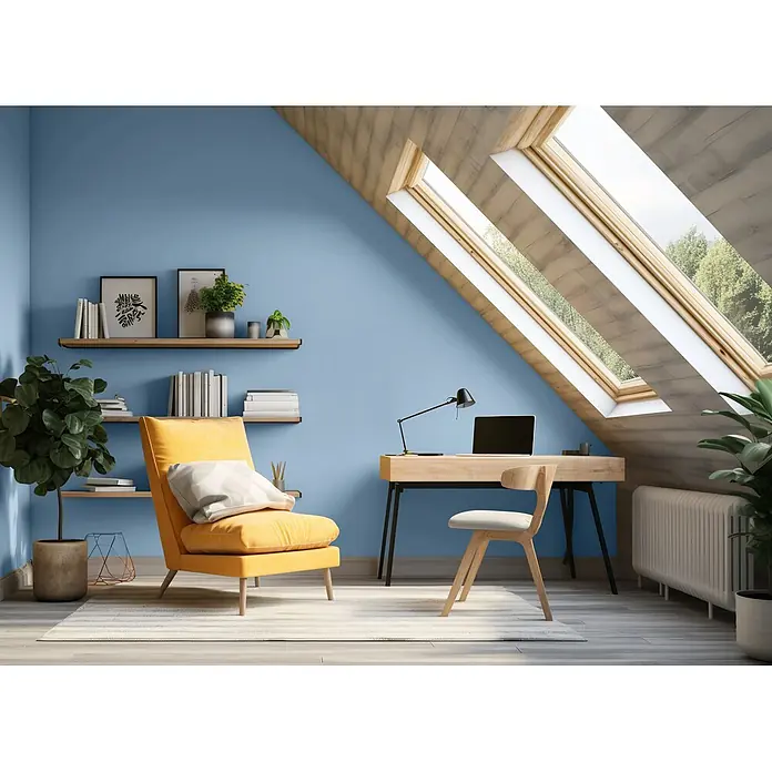 Caleo Color Wandfarbe Lehmfarbe Morgennebel - Morgennebel, Matt, 5 l - Helles Dachzimmer mit gelbem Sessel, Holzschreibtisch mit Laptop und Dachfenstern vor blauer Wand.