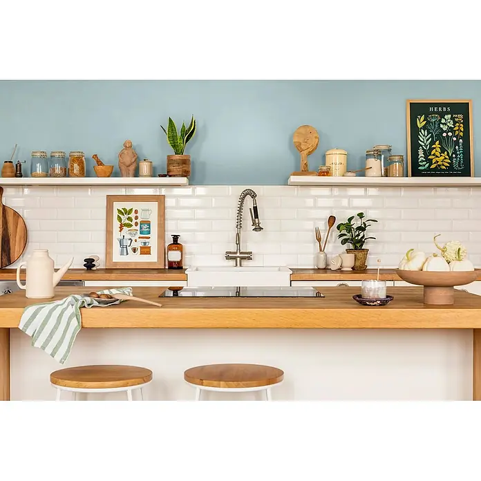 Caleo Color Wandfarbe Lehmfarbe Eisenherz - Eisenherz, Matt, 0,15 l - Helle Küche mit heller Holztheke, weißen Metrofliesen, blauer Wand und offenen Regalen. Mit Spüle, Herd und Hockern.