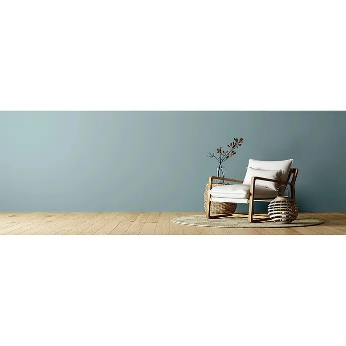 Caleo Color Wandfarbe Lehmfarbe Traumsand - Traumsand, Matt, 2,25 l - Moderner Sessel mit weißen Kissen und hellem Holzrahmen, auf einem Teppich in einem minimalistischen Raum.