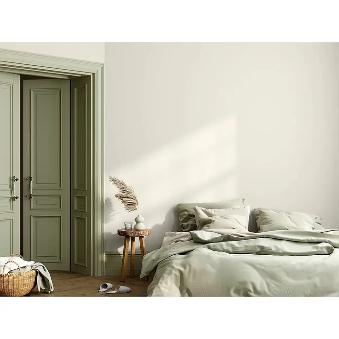 Caleo Color Wandfarbe Lehmfarbe Naturweiß - Naturweiß, Matt, 10 l - Ein gemütliches Schlafzimmer mit einem Bett mit salbeigrüner Bettdecke und Kissen, einem rustikalen Holznachttisch und salbeigrünen Kassettentüren.