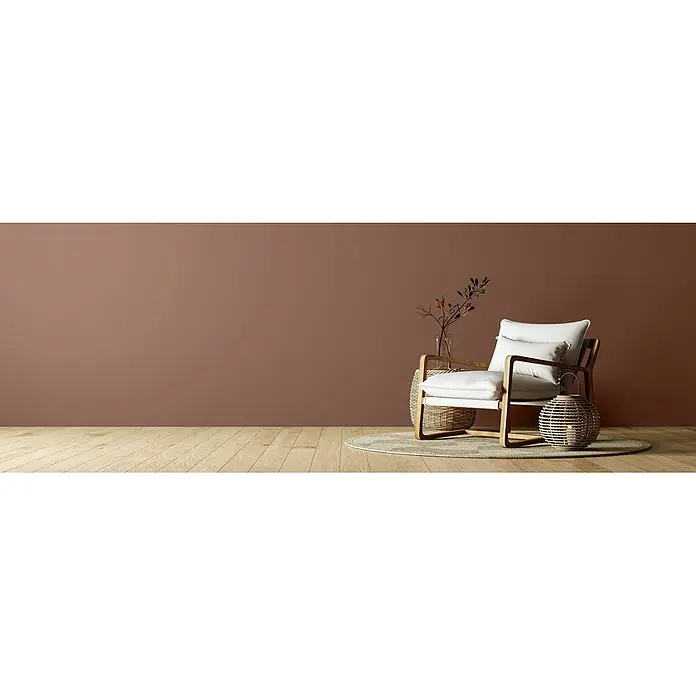 Caleo Color Wandfarbe Lehmfarbe Bärentatze - Bärentatze, Matt, 2,25 l - Ein stilvoller weißer Sessel mit Holzrahmen in einem modernen Wohnzimmer mit warmbraunen Wänden und Holzboden, ergänzt durch Naturdekor.