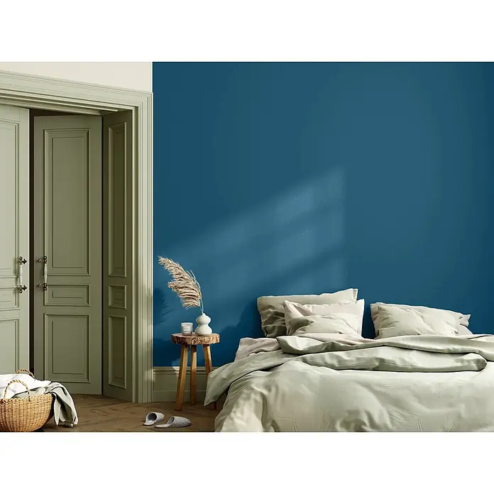 Caleo Color Wandfarbe Lehmfarbe Walgesang - Walgesang, Matt, 5 l - Hellgrüne Bettwäsche auf einem Bett in einem modernen Schlafzimmer mit blauer Wand, die eine ruhige Schlafumgebung schafft.