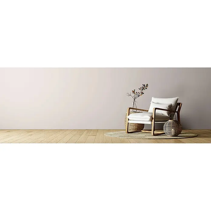 Caleo Color Wandfarbe Lehmfarbe Mondstein - Mondstein, Matt, 5 l - Moderner Sessel mit weißen Kissen und hellem Holzrahmen in einem minimalistischen Raum mit Rattan-Beistelltisch und Bodenlaterne.