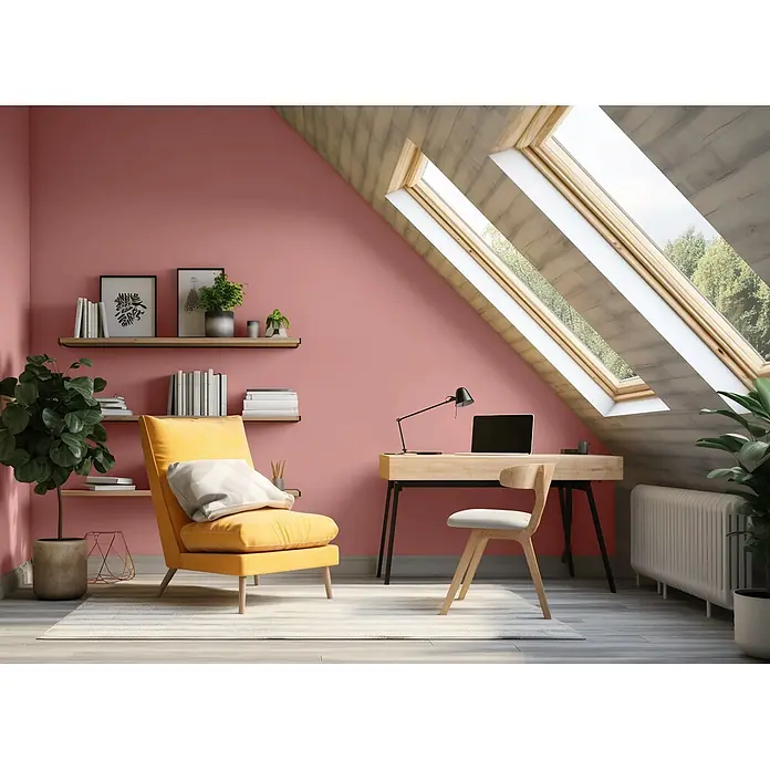 Caleo Color Wandfarbe Lehmfarbe Sommerabend - Sommerabend, Matt, 5 l - Dachboden-Homeoffice mit hellem Holzschreibtisch, Stuhl und gelbem Sessel, vor rosa Wänden und unter Dachfenstern.