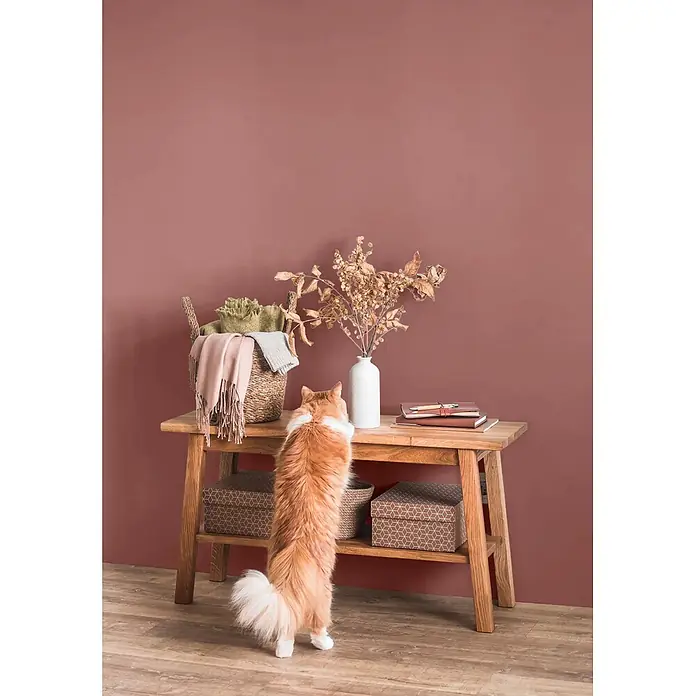 Caleo Color Wandfarbe Lehmfarbe Sommerabend - Sommerabend, Matt, 5 l - Konsolentisch aus hellem Holz mit Ablagefläche, dekoriert mit Korb und Vase in einem gemütlichen Interieur.