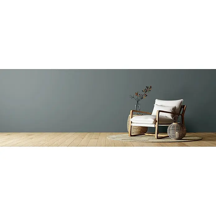 Caleo Color Wandfarbe Lehmfarbe Eukalyptus - Eukalyptus, Matt, 5 l - Moderner Sessel mit Holzrahmen, heller Polsterung, Vase, Ästen und Körben in minimalistischem Raum mit graublauer Wand und Holzboden.