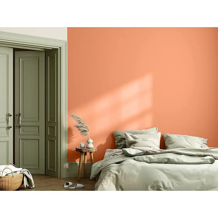 Caleo Color Wandfarbe Lehmfarbe Papaya - Papaya, Matt, 5 l - Ein Schlafzimmer mit korallenfarbener Wand, salbeigrüner Bettwäsche und passenden Türen für ein stimmiges Gesamtbild.