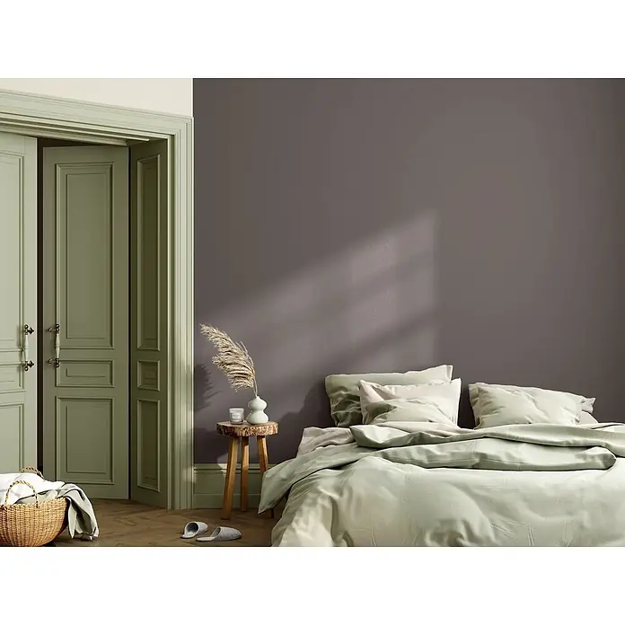 Caleo Color Wandfarbe Lehmfarbe Hochmoor - Hochmoor, Matt, 10 l - Hellgrüner Bettbezug und Kissen auf einem Bett in einem Schlafzimmer mit salbeigrünen Türen.