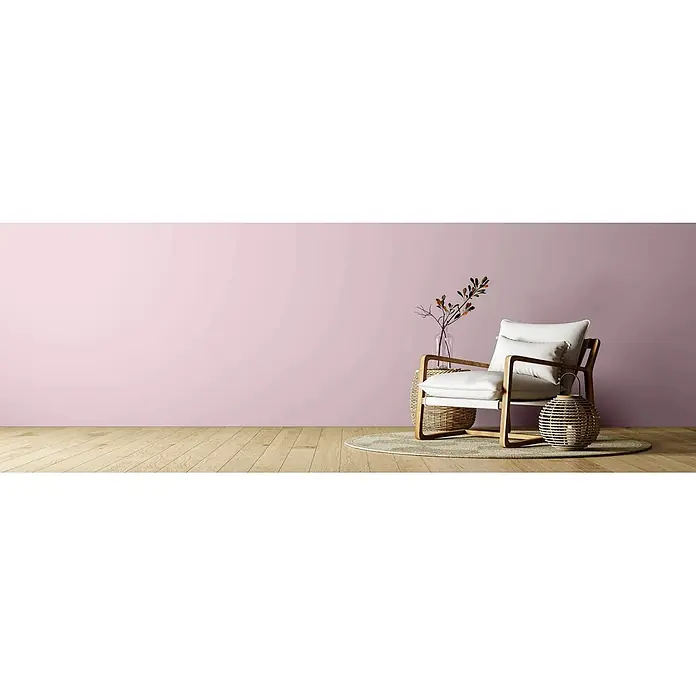 Caleo Color Wandfarbe Lehmfarbe Blütenzauber - Blütenzauber, Matt, 5 l - Moderner Sessel mit weißen Kissen und Holzrahmen in einem rosa Raum mit Vase und Laterne auf einem runden Teppich.