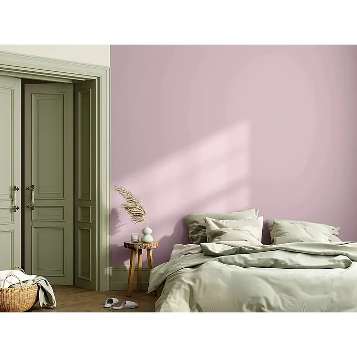 Caleo Color Wandfarbe Lehmfarbe Blütenzauber - Blütenzauber, Matt, 5 l - Hellgrüne Bettwäsche auf einem Bett in einem Schlafzimmer mit rosafarbenen Wänden und grünen Türen.