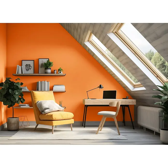 Caleo Color Wandfarbe Lehmfarbe Wüstenfuchs - Wüstenfuchs, Matt, 2,25 l - Lebendiges Dachbüro mit orangefarbenen Wänden, Holzschreibtisch, Stuhl und gemütlichem gelbem Sessel unter großen Dachfenstern.