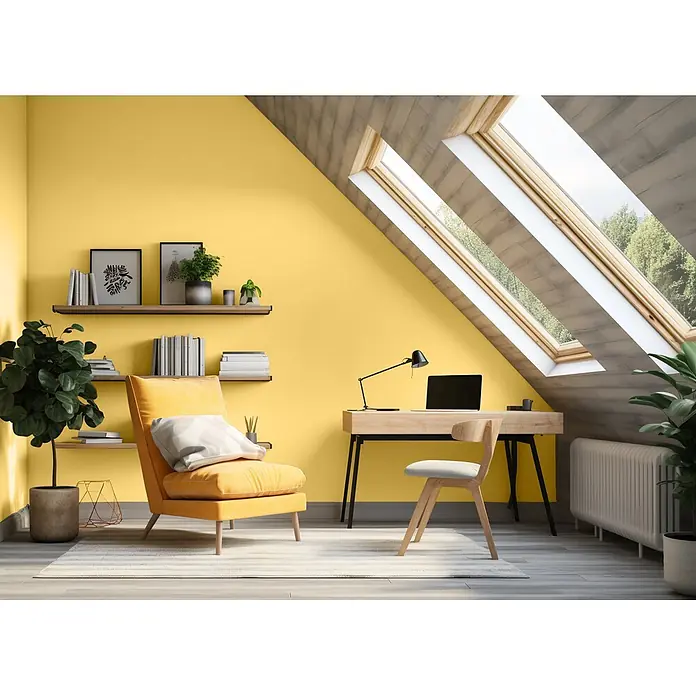 Caleo Color Wandfarbe Lehmfarbe Kükenflaum - Kükenflaum, Matt, 2,25 l - Ein sonniges Homeoffice mit gelben Wänden, hellem Holzschreibtisch, Stuhl und einem gemütlichen gelben Sessel, beleuchtet durch Dachfenster.