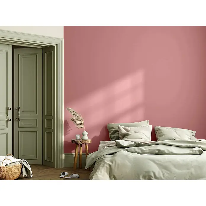 Caleo Color Wandfarbe Lehmfarbe Rosenquarz - Rosenquarz, Matt, 10 l - Hellgrüne Bettwäsche auf einem Bett in einem Schlafzimmer mit rosafarbener Wand und grünen Türen, für ein gemütliches Ambiente.
