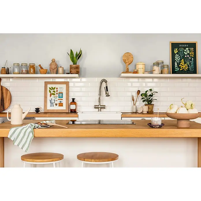 Caleo Color Wandfarbe Lehmfarbe Raureif - Raureif, Matt, 10 l - Eine moderne Küche mit hellen Holzarbeitsplatten, weißen Metrofliesen und offenen Regalen mit Küchenaccessoires und Pflanzen.